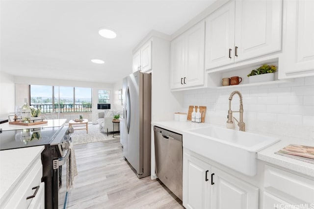 kitchen with sink, light hardwood / wood-style floors, white cabinets, and appliances with stainless steel finishes