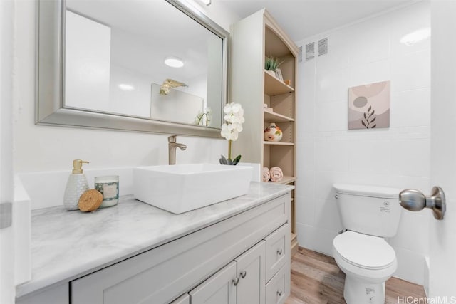 bathroom featuring hardwood / wood-style flooring, vanity, toilet, and tile walls