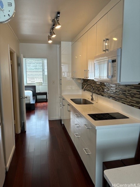 kitchen with black electric stovetop, sink, dark hardwood / wood-style flooring, white cabinets, and tasteful backsplash