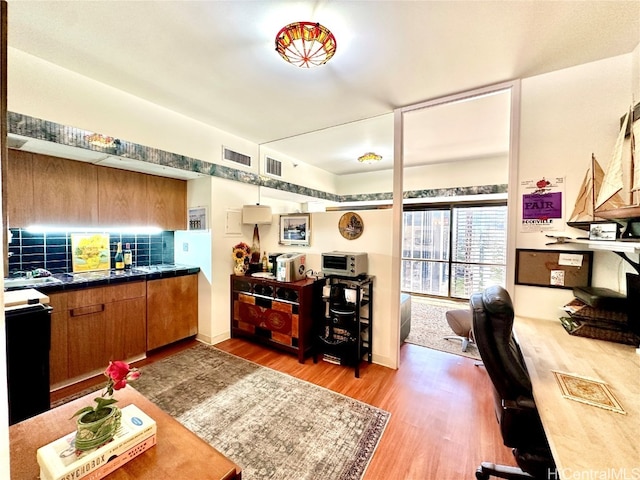 kitchen with tile countertops, hardwood / wood-style floors, black / electric stove, and decorative backsplash