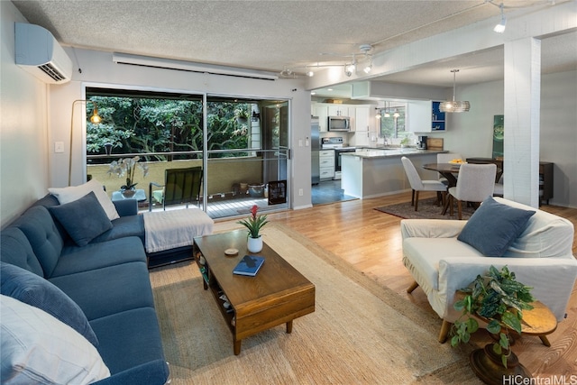 living room featuring a textured ceiling, light wood-type flooring, and a wall mounted AC