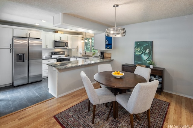 dining area with a notable chandelier, hardwood / wood-style floors, a textured ceiling, and sink