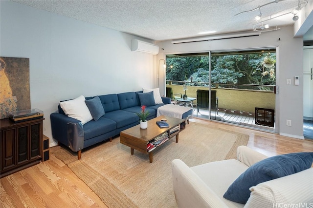 living room featuring a wall mounted air conditioner, a textured ceiling, and light hardwood / wood-style flooring