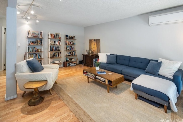 living room featuring a textured ceiling, light wood-type flooring, rail lighting, and a wall mounted AC