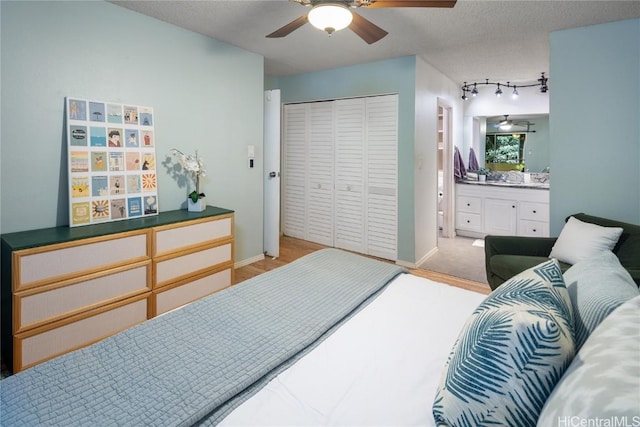 bedroom featuring a textured ceiling, ensuite bathroom, a closet, and ceiling fan