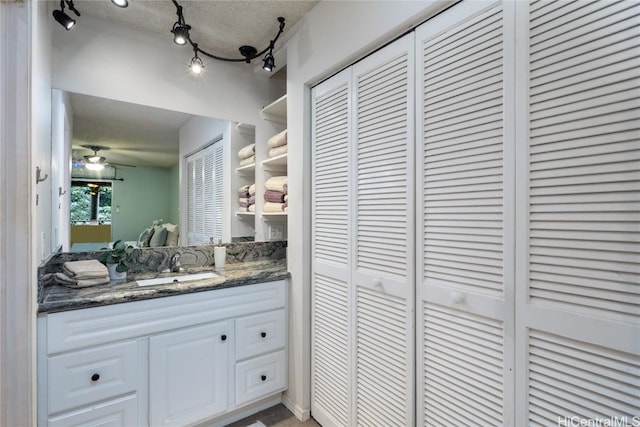 bathroom with vanity, a textured ceiling, rail lighting, and ceiling fan