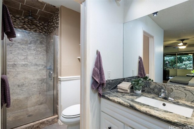 bathroom with an enclosed shower, vanity, ceiling fan, and toilet