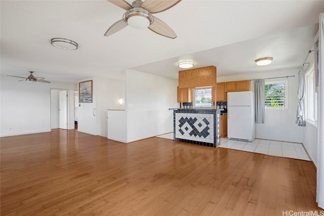 unfurnished living room featuring ceiling fan and light wood-type flooring