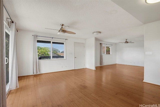 empty room with a healthy amount of sunlight, a textured ceiling, and hardwood / wood-style flooring