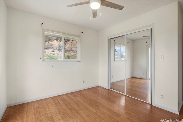 unfurnished bedroom featuring ceiling fan, a closet, a textured ceiling, and hardwood / wood-style flooring