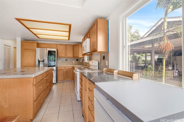 kitchen with decorative backsplash, a kitchen island, a healthy amount of sunlight, and white appliances