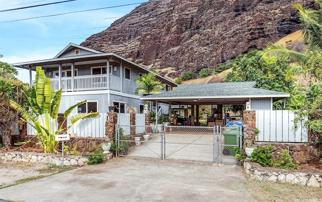 84-280 Holt St, Waianae, HI 96792 - view of front of house featuring a gate, concrete driveway, a balcony, a detached carport, and stone siding