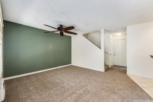 empty room featuring ceiling fan, light tile patterned floors, and a textured ceiling