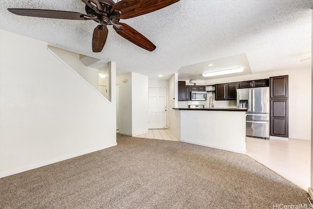 unfurnished living room featuring ceiling fan, sink, a textured ceiling, and light carpet