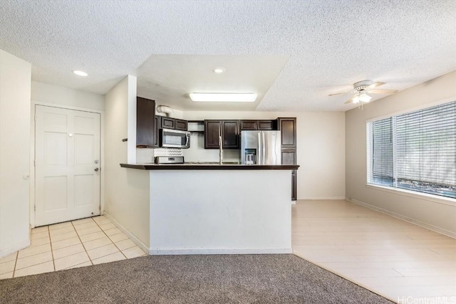 kitchen featuring light tile patterned floors, ceiling fan, appliances with stainless steel finishes, dark brown cabinets, and a textured ceiling