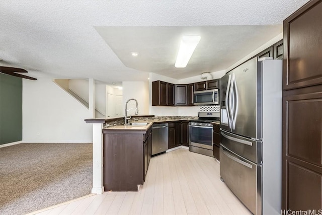 kitchen featuring a textured ceiling, appliances with stainless steel finishes, kitchen peninsula, ceiling fan, and dark brown cabinets