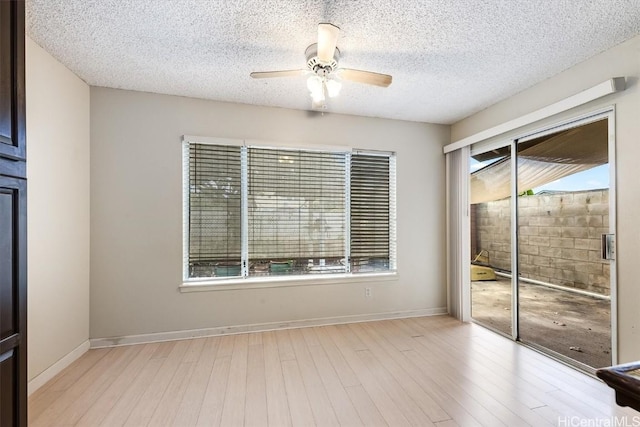 spare room with ceiling fan, a textured ceiling, and light wood-type flooring