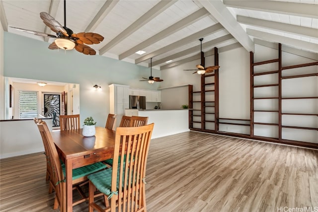 dining area with light wood-type flooring and vaulted ceiling with beams