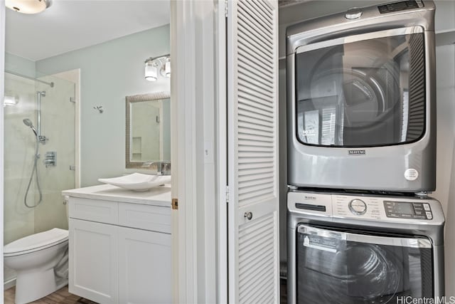 laundry room with stacked washing maching and dryer, wood-type flooring, and sink