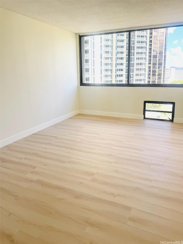 1255 Nuuanu Ave Unit E1414, Honolulu, HI 96817 - unfurnished room featuring healthy amount of natural light, light wood-style flooring, baseboards, and a textured ceiling