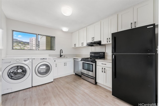 kitchen with appliances with stainless steel finishes, white cabinets, separate washer and dryer, and light wood-type flooring