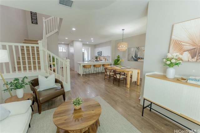 living room with an inviting chandelier, light hardwood / wood-style flooring, and sink