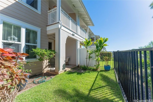 view of side of home with a balcony and a yard