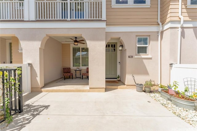 view of exterior entry with a patio area, ceiling fan, and a balcony