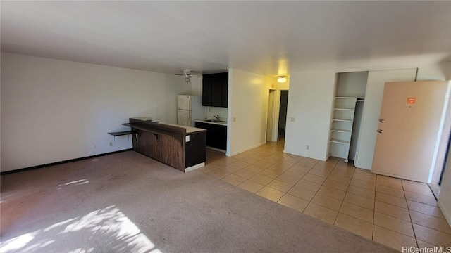 kitchen featuring white refrigerator, sink, light colored carpet, and kitchen peninsula