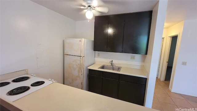 kitchen featuring light tile patterned flooring, cooktop, sink, white refrigerator, and ceiling fan