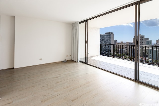 empty room with floor to ceiling windows and hardwood / wood-style flooring