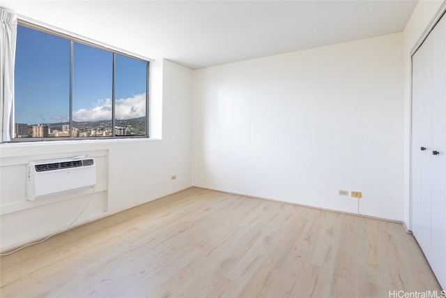 unfurnished living room featuring a wall mounted air conditioner and light hardwood / wood-style floors