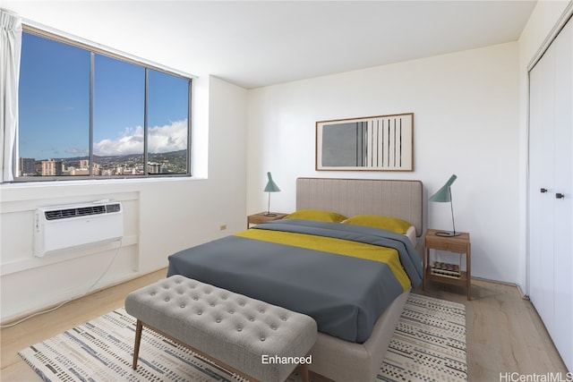 bedroom featuring a wall unit AC, a closet, and light hardwood / wood-style flooring