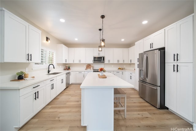 kitchen with a kitchen island, light wood-type flooring, white cabinetry, and stainless steel appliances