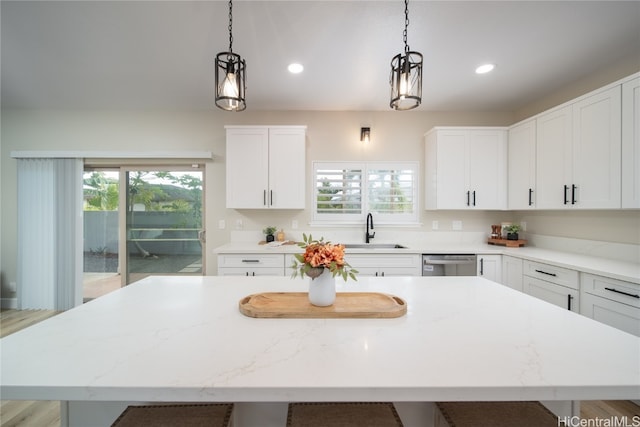 kitchen with a wealth of natural light, pendant lighting, stainless steel dishwasher, and light wood-type flooring