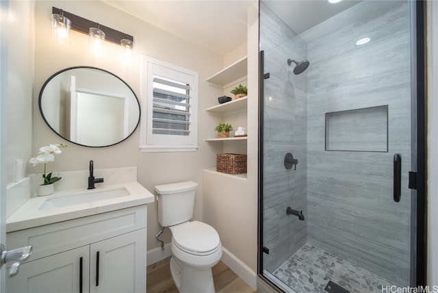 bathroom featuring wood-type flooring, vanity, toilet, and an enclosed shower