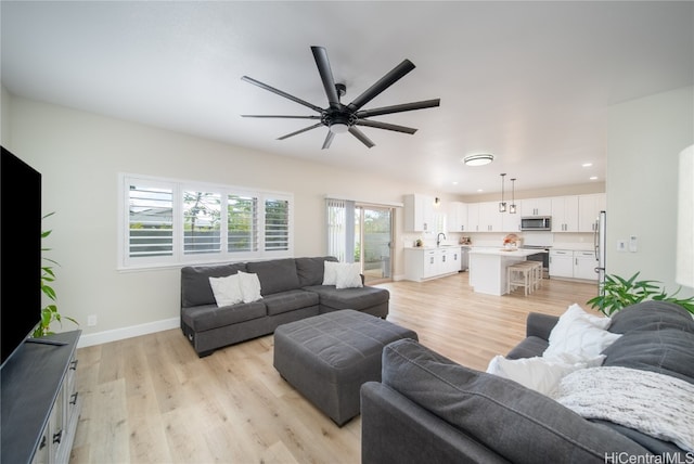 living room featuring ceiling fan, light wood-type flooring, and sink