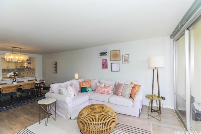 living room with light hardwood / wood-style floors and a notable chandelier