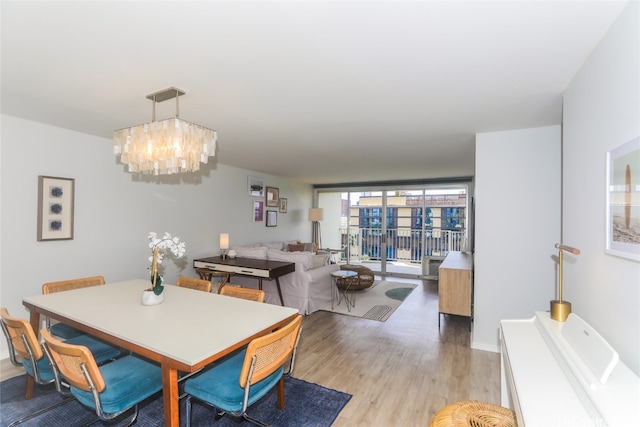 dining space with light hardwood / wood-style floors, an inviting chandelier, and floor to ceiling windows