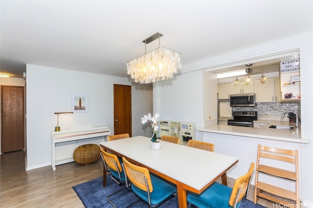 dining space featuring a chandelier, sink, and light wood-type flooring