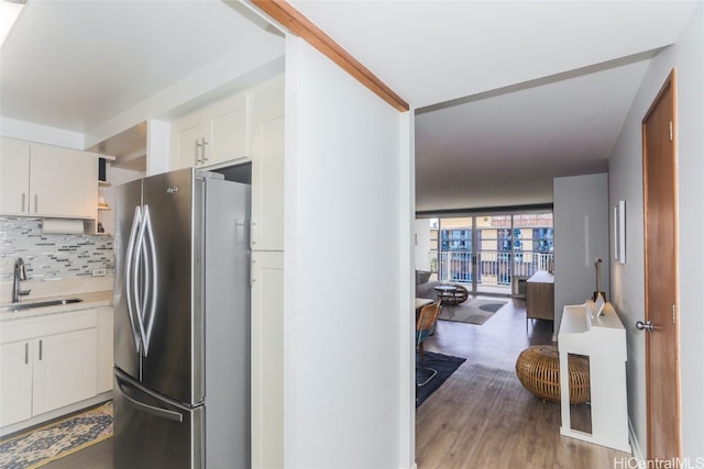 kitchen featuring white cabinets, sink, light wood-type flooring, and stainless steel refrigerator