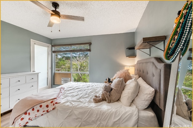 bedroom featuring light hardwood / wood-style flooring, cooling unit, a textured ceiling, and ceiling fan