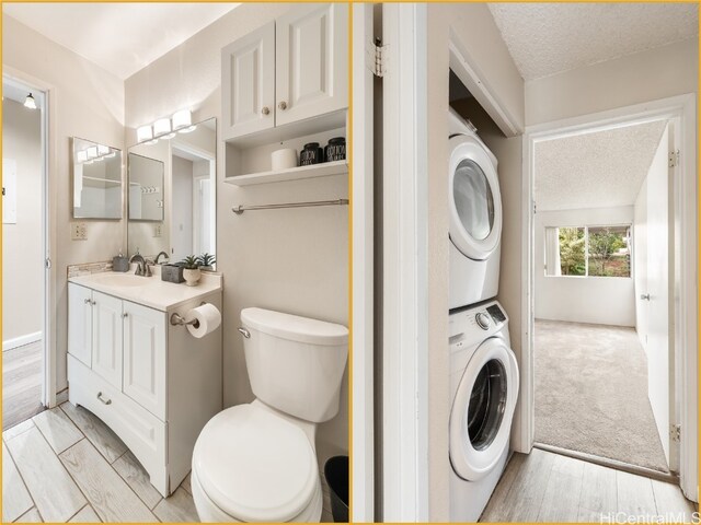 bathroom featuring hardwood / wood-style floors, a textured ceiling, toilet, vanity, and stacked washer and clothes dryer