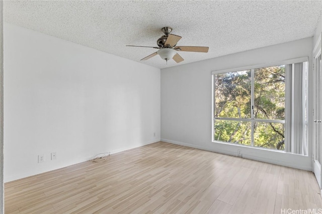 empty room with ceiling fan, a healthy amount of sunlight, a textured ceiling, and light wood-type flooring