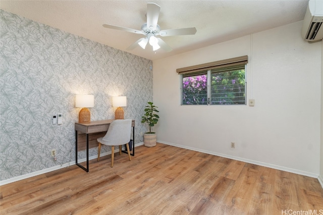 office area with ceiling fan, a textured ceiling, light hardwood / wood-style flooring, and a wall unit AC