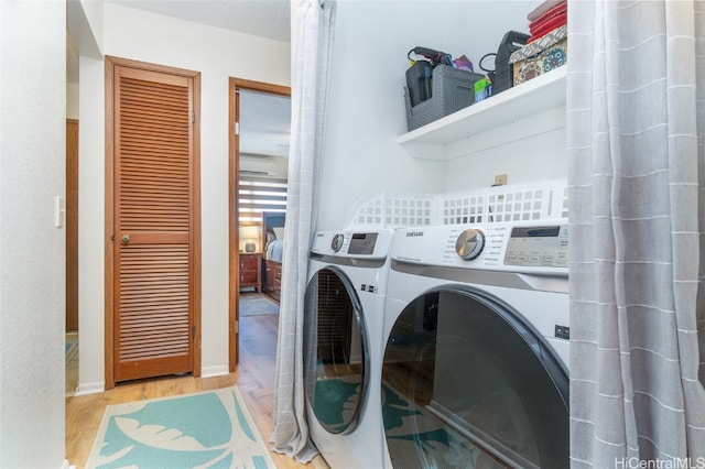 clothes washing area with light hardwood / wood-style flooring and washer and clothes dryer