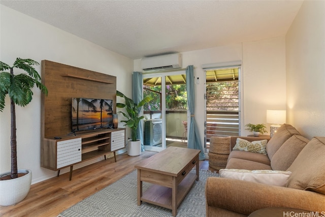 living room featuring a wall mounted AC, a textured ceiling, and hardwood / wood-style floors