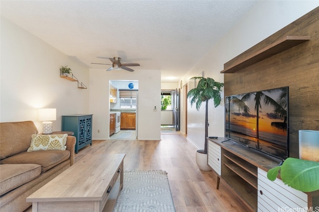 living room with light hardwood / wood-style floors, a textured ceiling, and ceiling fan