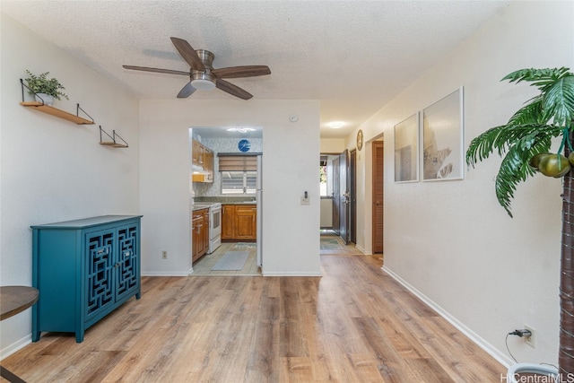 living room featuring light hardwood / wood-style flooring, a textured ceiling, and ceiling fan