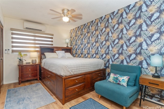 bedroom with light hardwood / wood-style floors, a wall mounted AC, and ceiling fan